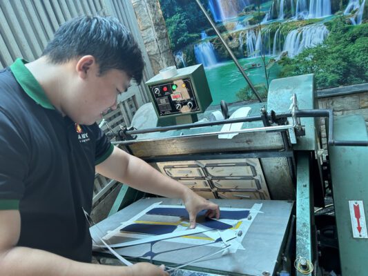 Nhân viên công ty đang gia công cắt bìa menu