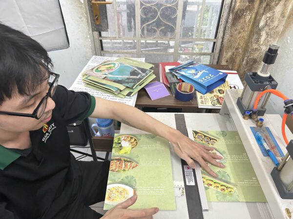 nhân viên Gia Huy đang làm menu bìa cứng